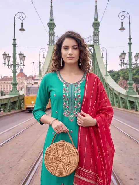 Model in a teal kurta with a straw bag on a city bridge
