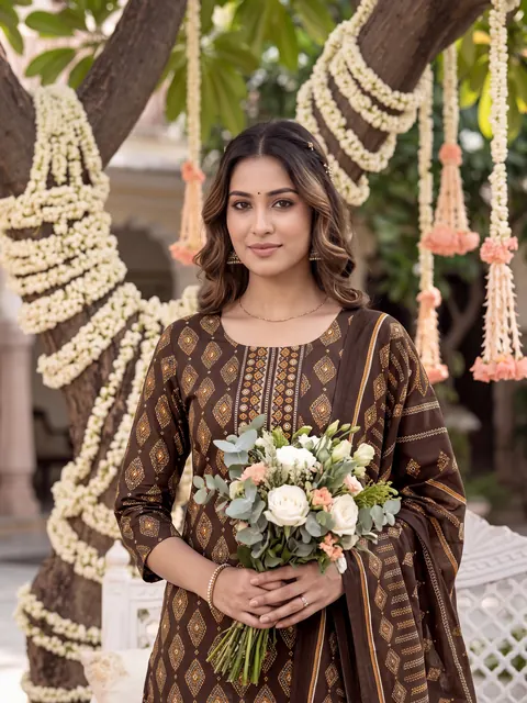 Model in a brown printed kurta set holding a bouquet under jasmine garlands — made with Drapify